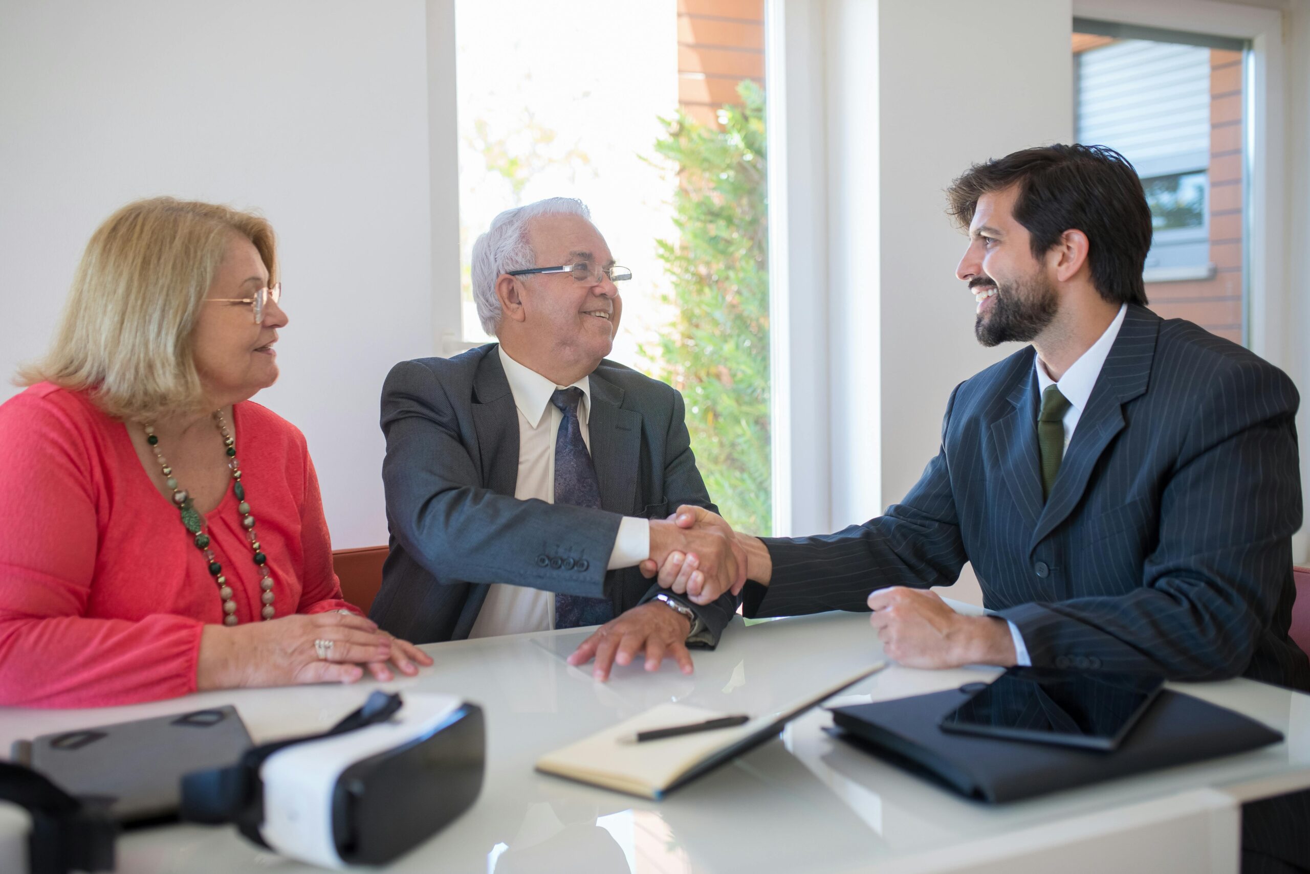 REALTOR sitting with a couple shaking hands.