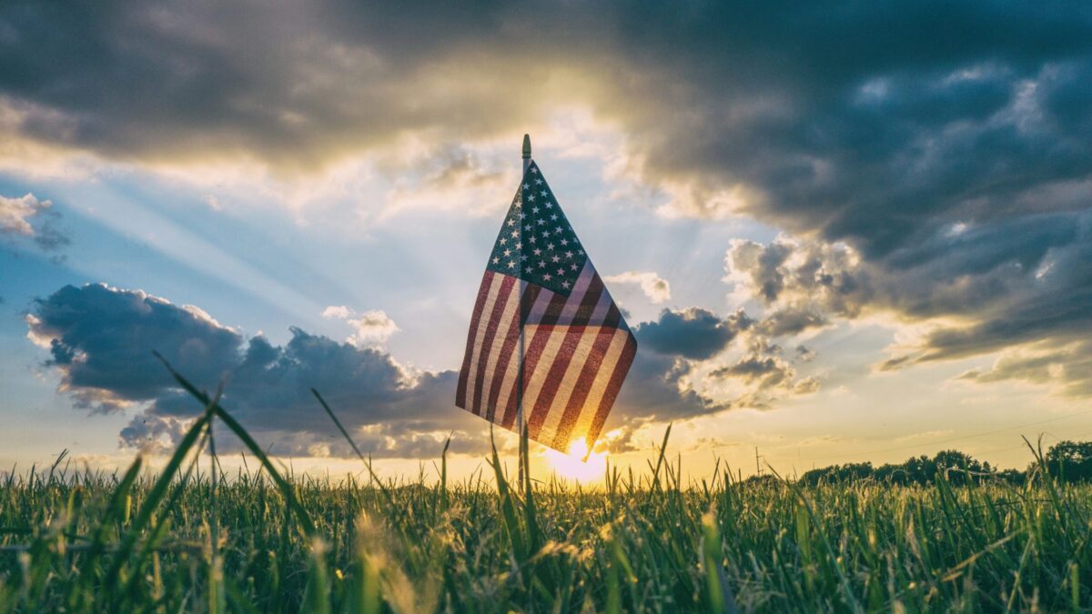 American flag in a field of grass at sunset
