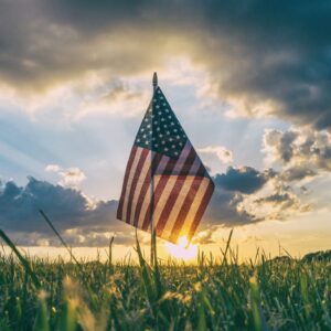 American flag in a field of grass at sunset